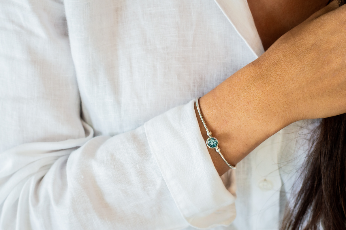 Zilveren as armband met in het midden een ornamentje, gedenksieraad, alle