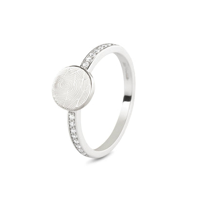 Ring witgoud 2 mm breed voorzien van een vingerafdruk/gravure, de ringband is in de bovenste helft afgewerkt met zirkonia's. witgoud