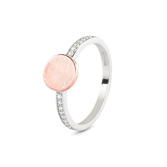 Breedte ringband: 2 mm, Diameter bovenzijde ring: 7.7 mm  Levertijd: 5 weken. Zilveren ring voorzien van een 14 KT gouden vingerafdruk/gravure, de ringband is in de bovenste helft afgewerkt met zirkonia's. Het is een tijdloos gedenksieraad en is te bestellen in  14 KT geelgoud en 14 KT roségoud.