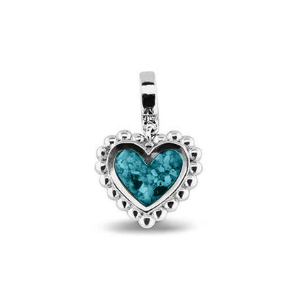Hartvormige asbedel, die aan de voorzijde zichtbaar gevuld wordt met as of haar. Het vullen en sealen met een keuze in 20 kleuren, wordt in onze ambachtelijke edelsmederij gedaan. Turquoise