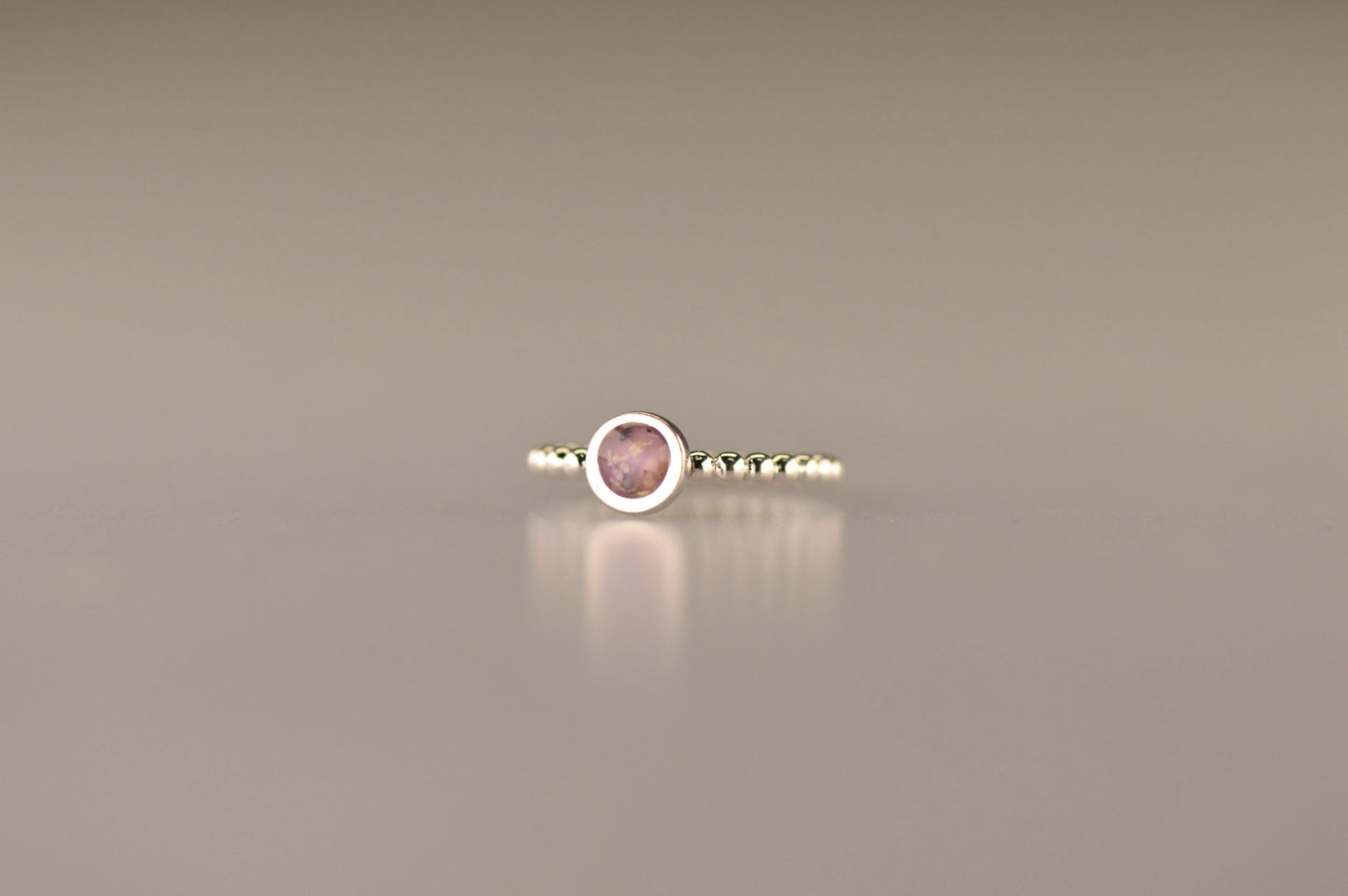 Diameter rondje: 6 mm, Ringband: 2 mm. Ring als gedenksieraad met een rondje er boven op , waar zichtbaar as of haar  in verwerkt wordt. Alle