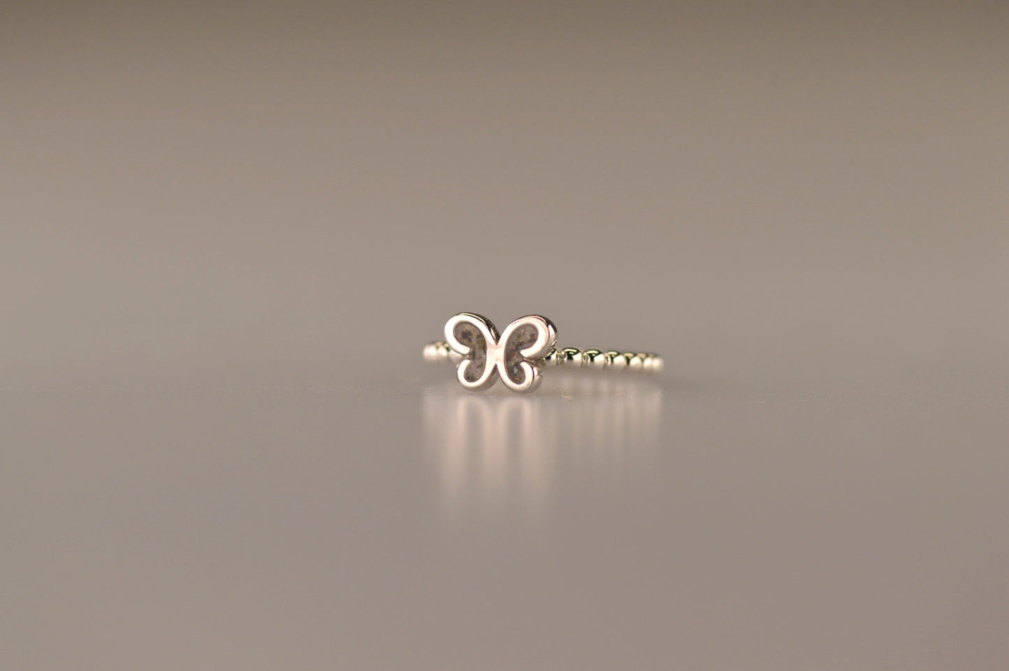 Afmeting vlinder: 8x6 mm, Ringband: 2 mm. Bolletjes ring als gedenksieraad met een vlinder er boven op , waar zichtbaar as of haar  in verwerkt wordt. Alle