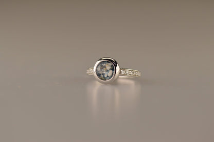 Gedenksieraad, ring 3 mm waar aan de bovenzijde zichtbaar as of haar verwerkt wordt. In de bovenste helft van de ringband zijn zirkonia's of diamanten naar keuze gezet. Alle