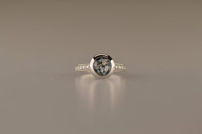 Gedenksieraad, ring 3 mm waar aan de bovenzijde zichtbaar as of haar verwerkt wordt. In de bovenste helft van de ringband zijn zirkonia's of diamanten naar keuze gezet. Alle