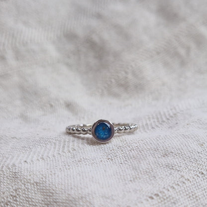 Diameter rondje: 6 mm, Ringband: 2 mm. Ring als gedenksieraad met een rondje er boven op , waar zichtbaar as of haar  in verwerkt wordt. Alle