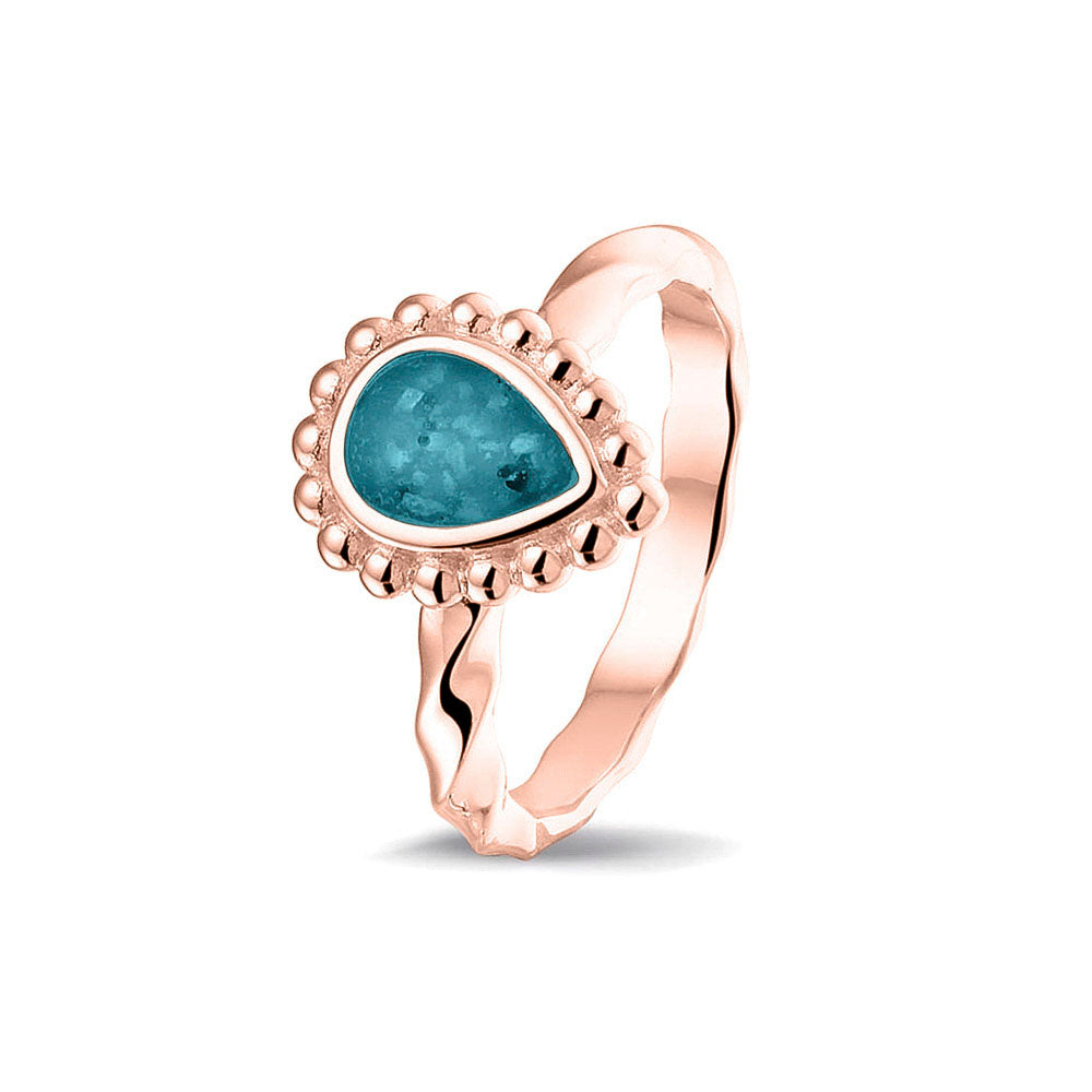Gedenksieraad, asring met gedraaide scheen waar aan de bovenzijde in druppelvorm met parelrand zichtbaar as of haar (of eventueel melktandjes of moedermelk) verwerkt wordt.turquoise