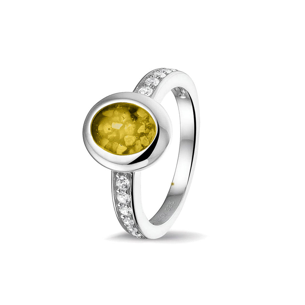 Gedenksieraad, ring 3 mm waar aan de ovale bovenzijde zichtbaar as of haar verwerkt wordt. In de bovenste helft van de ringband zijn zirkonia's of diamanten naar keuze gezet. Yellow