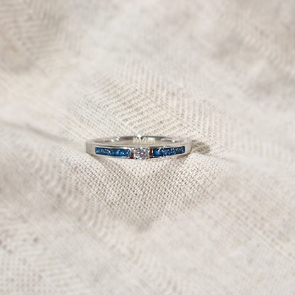 Gedenksieraad, ring 3 mm met (zirkonia of diamant), geflankeerd door twee compartimenten waar zichtbaar as of haar  in verwerkt wordt. Alle
