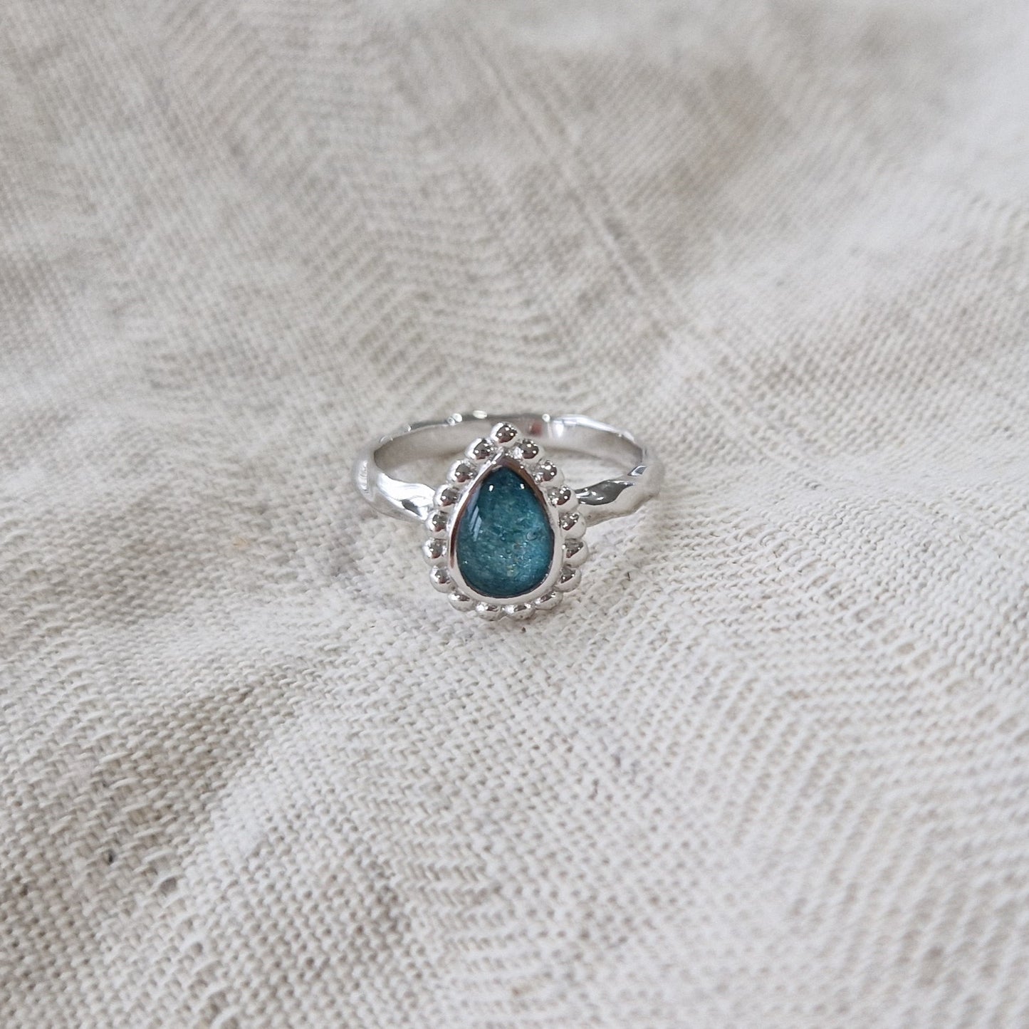 Gedenksieraad, asring met gedraaide scheen waar aan de bovenzijde in druppelvorm met parelrand zichtbaar as of haar (of eventueel melktandjes of moedermelk) verwerkt wordt.alle