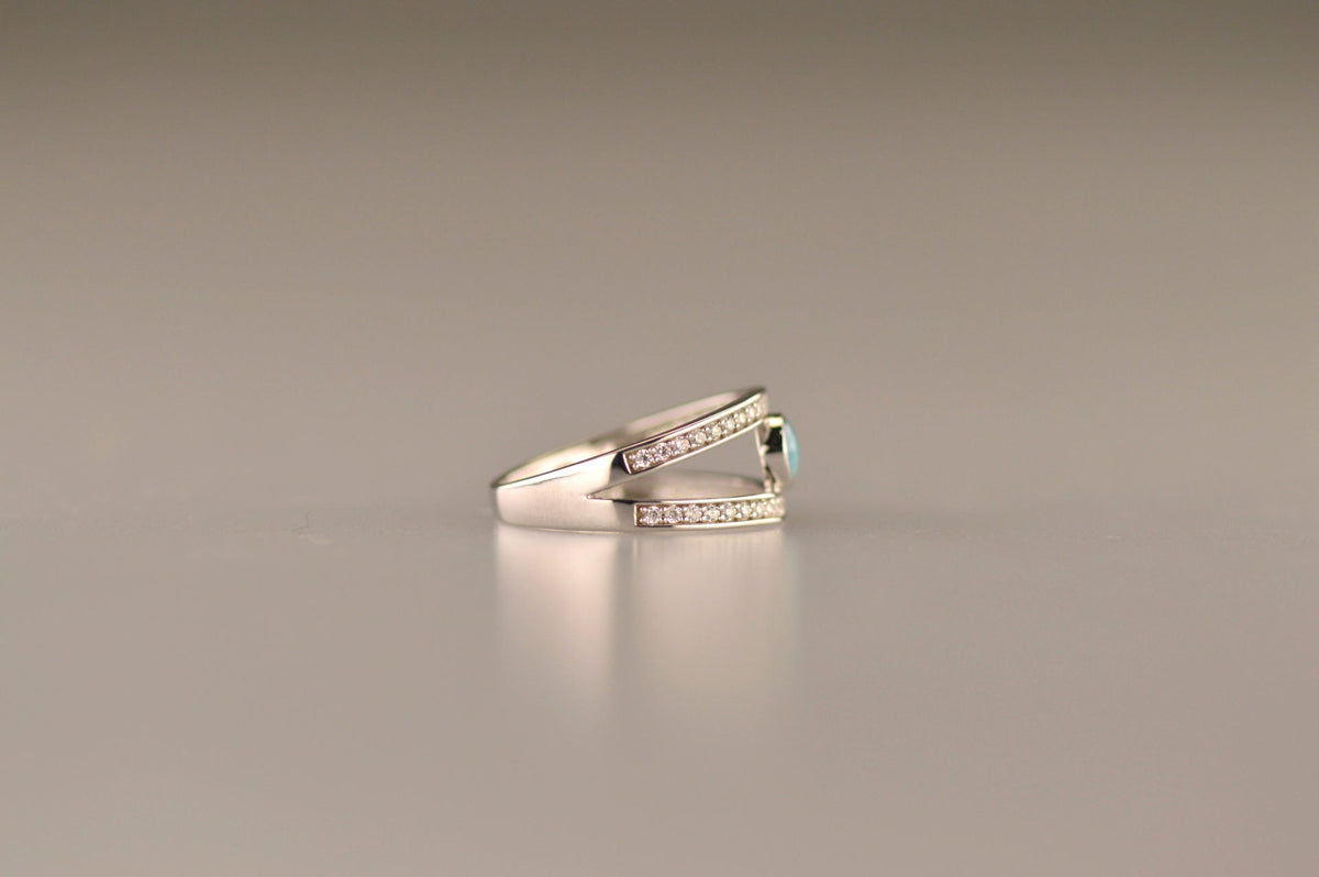 Gedenksieraad, ring waar aan de bovenzijde zichtbaar as of haar verwerkt wordt. In de bovenste helft van de ringband zijn subtiel edelstenen naar keuze gezet. Alle
